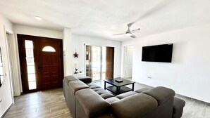 A modern living room with a sectional sofa, a coffee table, and a ceiling fan.