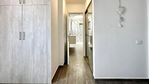 A hallway with a wardrobe, a bathroom with a stone backsplash, and a wall-mounted heart decoration.