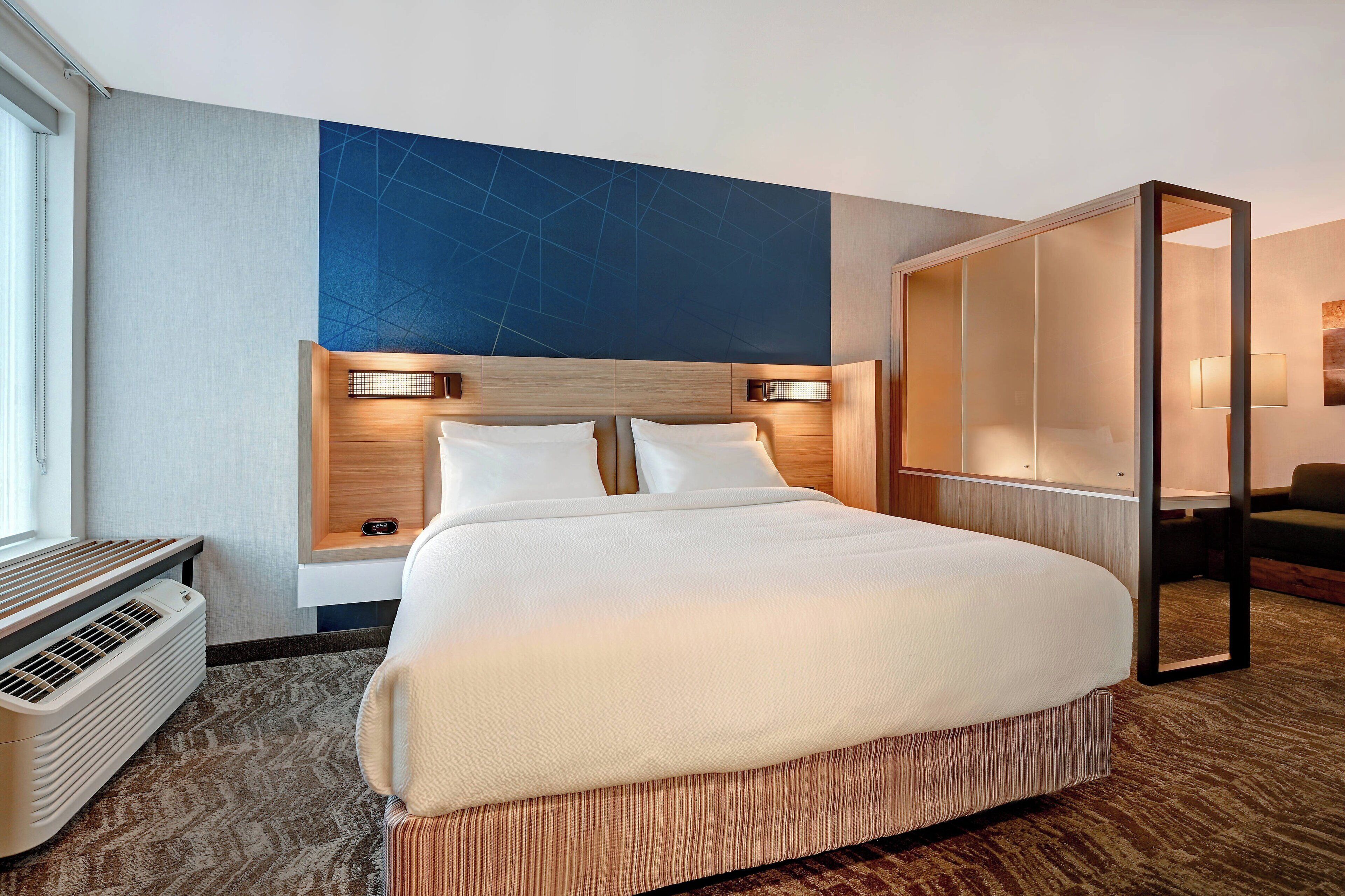 Habitación de hotel con una cama grande, lámparas de noche, un calentador y vistas al exterior.