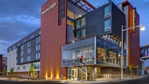 Een modern hotel met een opvallende rode en grijze gevel, grote ramen en een duidelijke ingang met een trap.