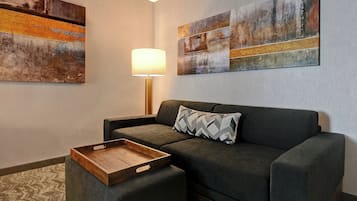 A modern living room with a grey sofa, a wooden side table, and two abstract paintings on the wall.