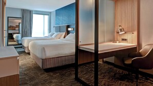 Een hotelkamer met twee bedden, een bureau, een stoel en een grote spiegel.