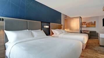 A hotel room with two beds, a sofa, a desk, and a large wall mural.