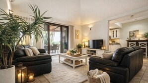 Un salon avec deux canapés en cuir noir, une table basse blanche et une grande plante en pot.