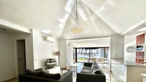 Ein modernes Wohnzimmer mit Flachbildfernseher, einer Couch und einem Essbereich mit einem Glastisch.