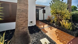 Ein Haus mit gefliestem Patio, Palmen und einem Kakteengarten.