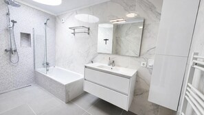 Une salle de bain moderne avec une baignoire, une douche et un meuble-lavabo.