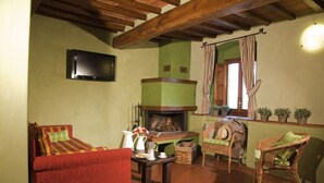 A cozy living room with a fireplace, a television mounted on the wall, and wicker furniture.
