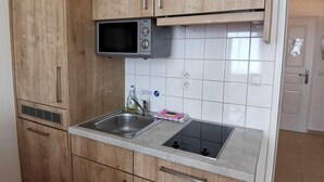 Eine Küche mit Holzschränken, einer Mikrowelle, einem Spülbecken und einem Herd.