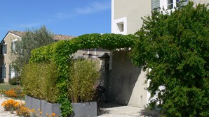 Un barrio residencial con una casa que tiene un porche cubierto, un camino de grava y un jardín con plantas en flor.