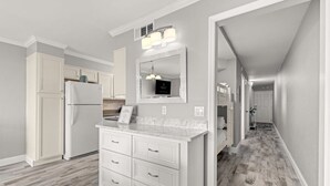 A modern kitchen with white cabinetry, a marble countertop, and a built-in oven.