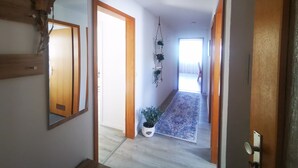 A hallway with wooden doors, a mirror, a hanging plant, and a patterned rug. - Vacation Apartment "Ländle" (Dauchingen)