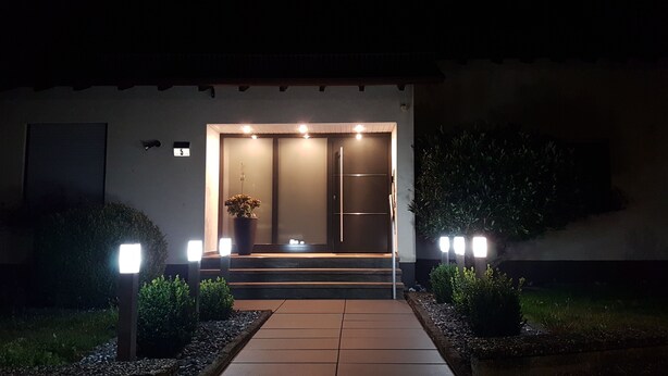 A modern entrance with a glass door, steps, and a potted plant. - Vacation Apartment "Ländle" (Dauchingen)