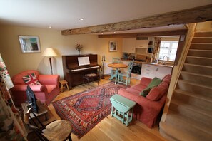Una sala de estar acogedora con un piano, un sofá, una mesita y una alfombra.