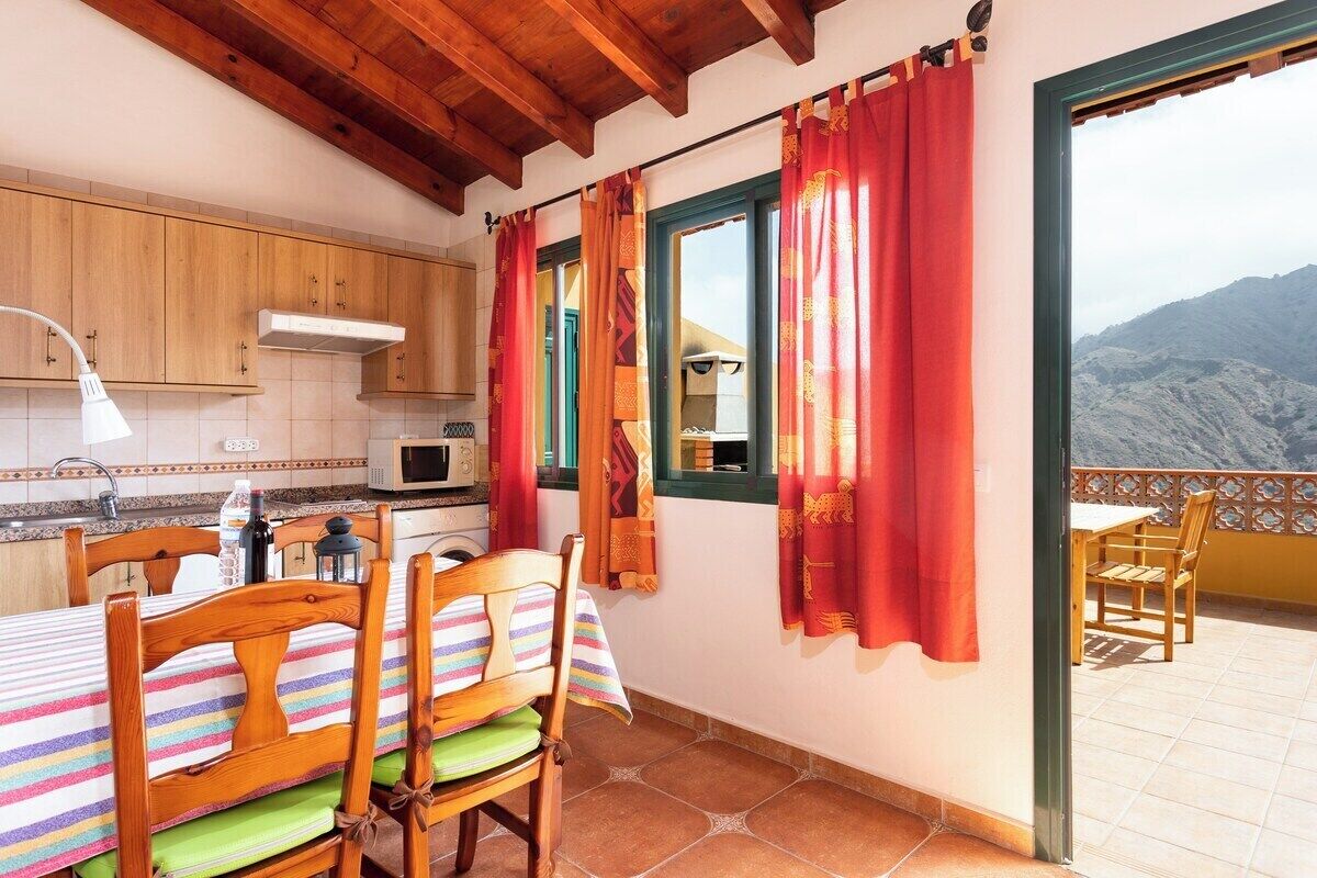 Una cucina con mobili in legno, un forno a microonde e un'area pranzo con tavolo e sedie.
