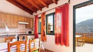 A kitchen with wooden cabinets, a microwave, and a dining area with a table and chairs.