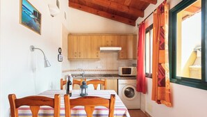 A compact kitchen with wooden cabinets, a microwave, and a washing machine.