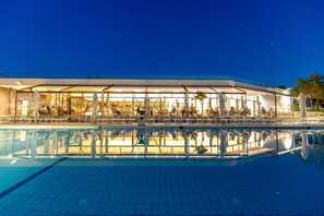 A modern hotel with a pool, lounge area, and outdoor seating.