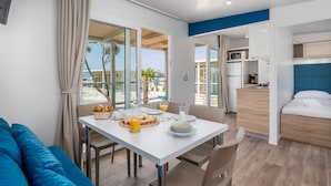 A modern, compact room with a dining table set for breakfast, a kitchenette, and a bed. - Mobile home Camping Omišalj (Omisalj)