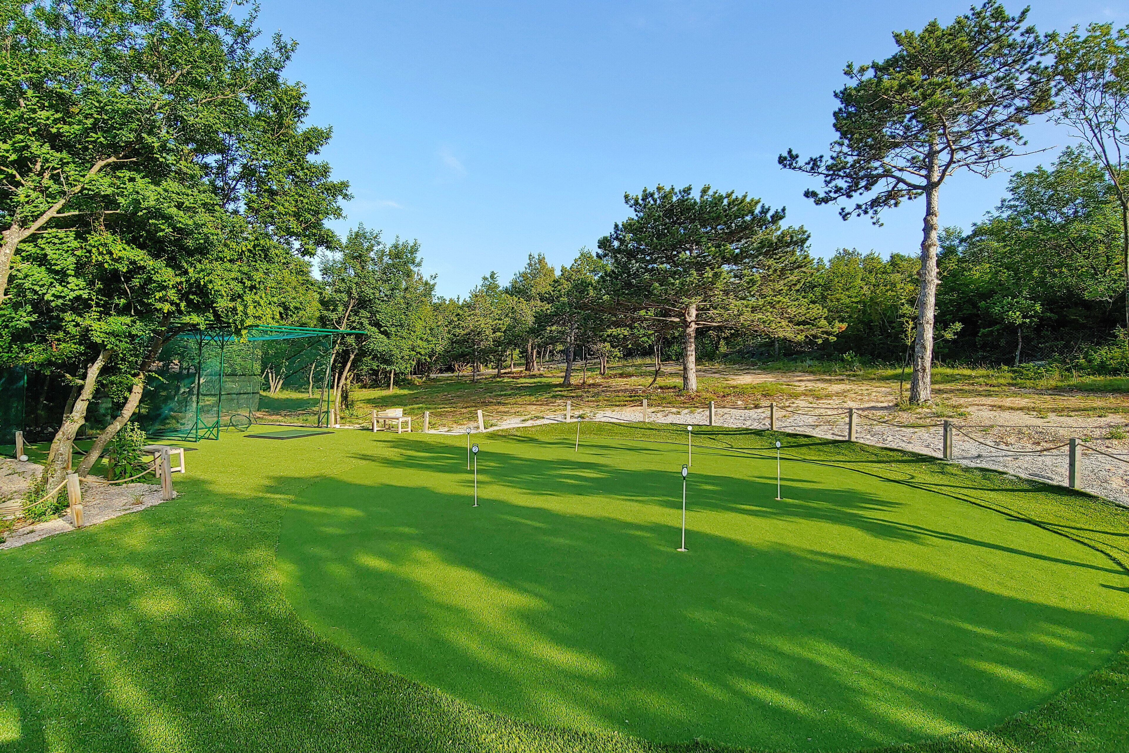 A golf course with a well-maintained green, sand bunkers, and a wooden fence.