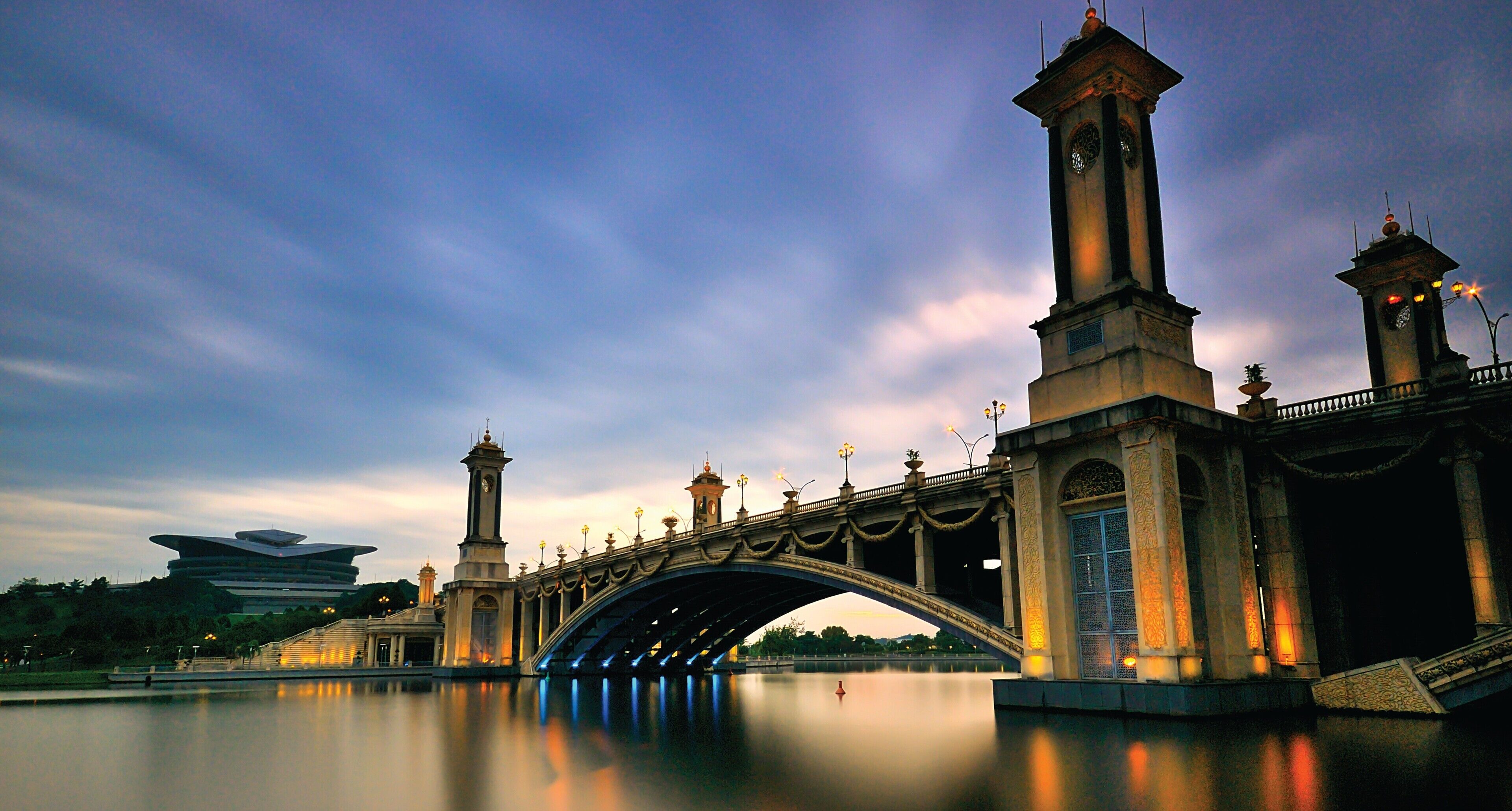A bridge with a clock tower and a pagoda-like structure in the background.