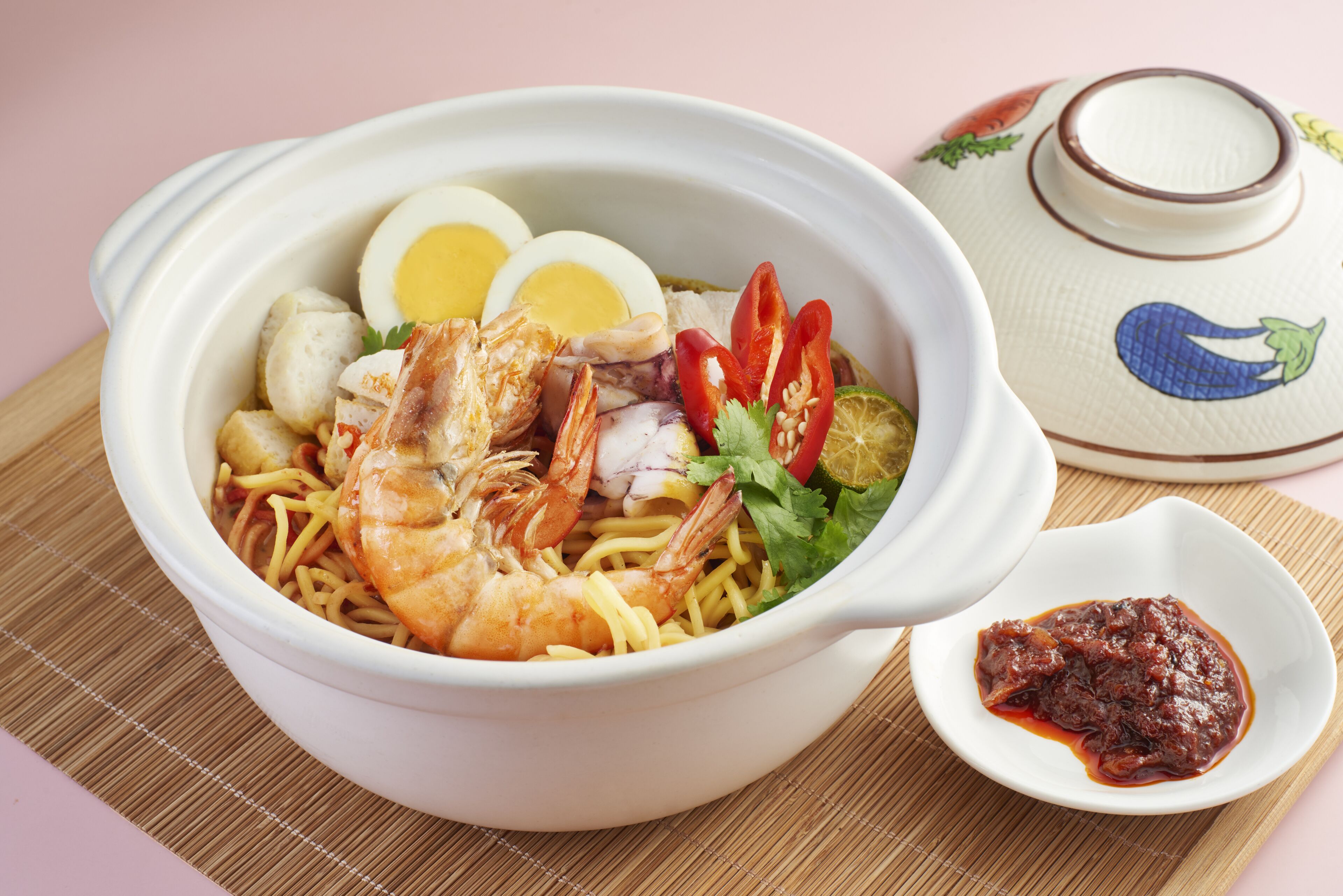 Un tazón de fideos con camarones, huevos y vegetales.