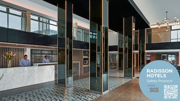 A modern hotel lobby with a reception desk, glass partitions, and a patterned floor. - Park Inn by Radisson Putrajaya (Bandar Baru Bangi)