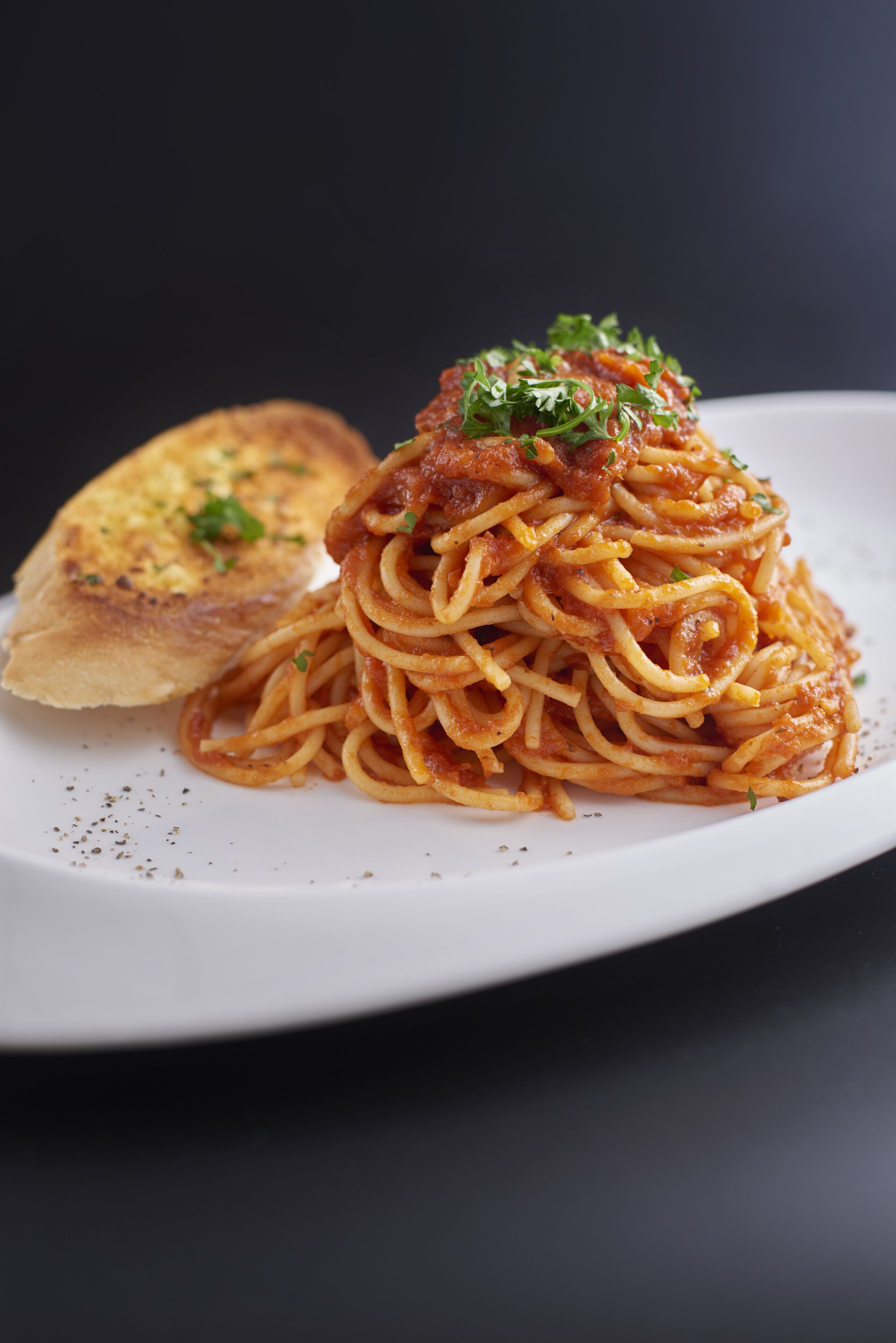 En tallerken spaghetti med tomatsovs og et stykke brød.