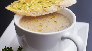 Une tasse de soupe blanche, accompagnée d’une tranche de pain.