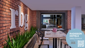 A restaurant with a brick wall and a sign reading "rbg". There is a table set with chairs and a vase of flowers. - Park Inn by Radisson Putrajaya (Bandar Baru Bangi)