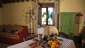 A cozy room with a red sofa, a table with copper pots and vegetables, and a green cabinet.