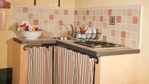 A kitchen with a tiled backsplash, a stove, and a hanging shelf with jars.