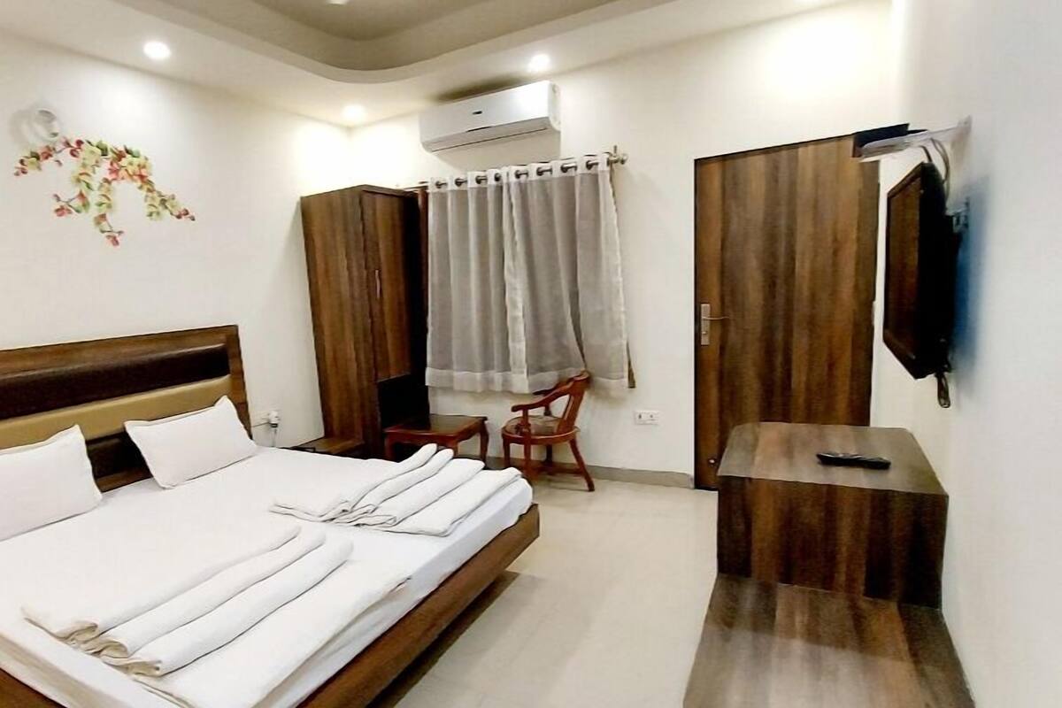 Un dormitorio con una cama, un armario de madera, un televisor montado en la pared y un ventilador de techo.