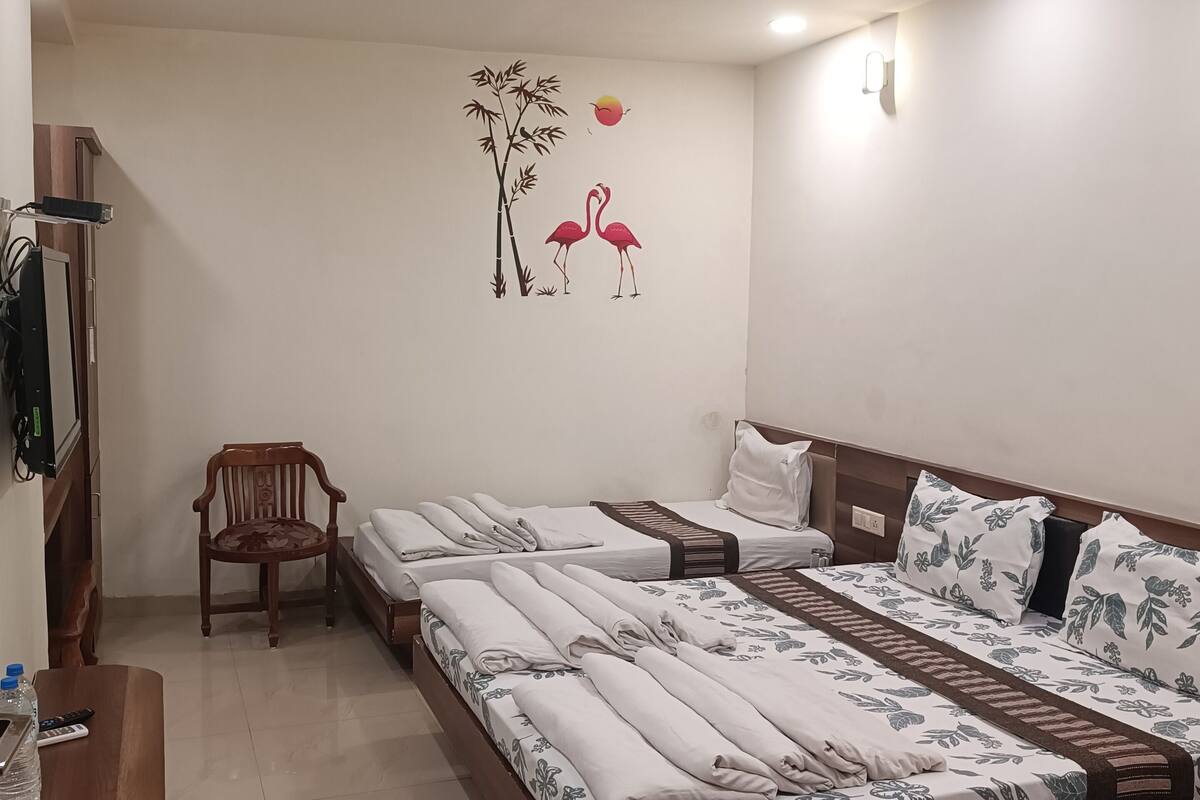 Habitación de hotel con dos camas, una silla de madera, un escritorio con computadora y un ventilador de techo.