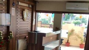 Un vestíbulo de hotel con mostrador de recepción, zona de estar y ventilador de techo.