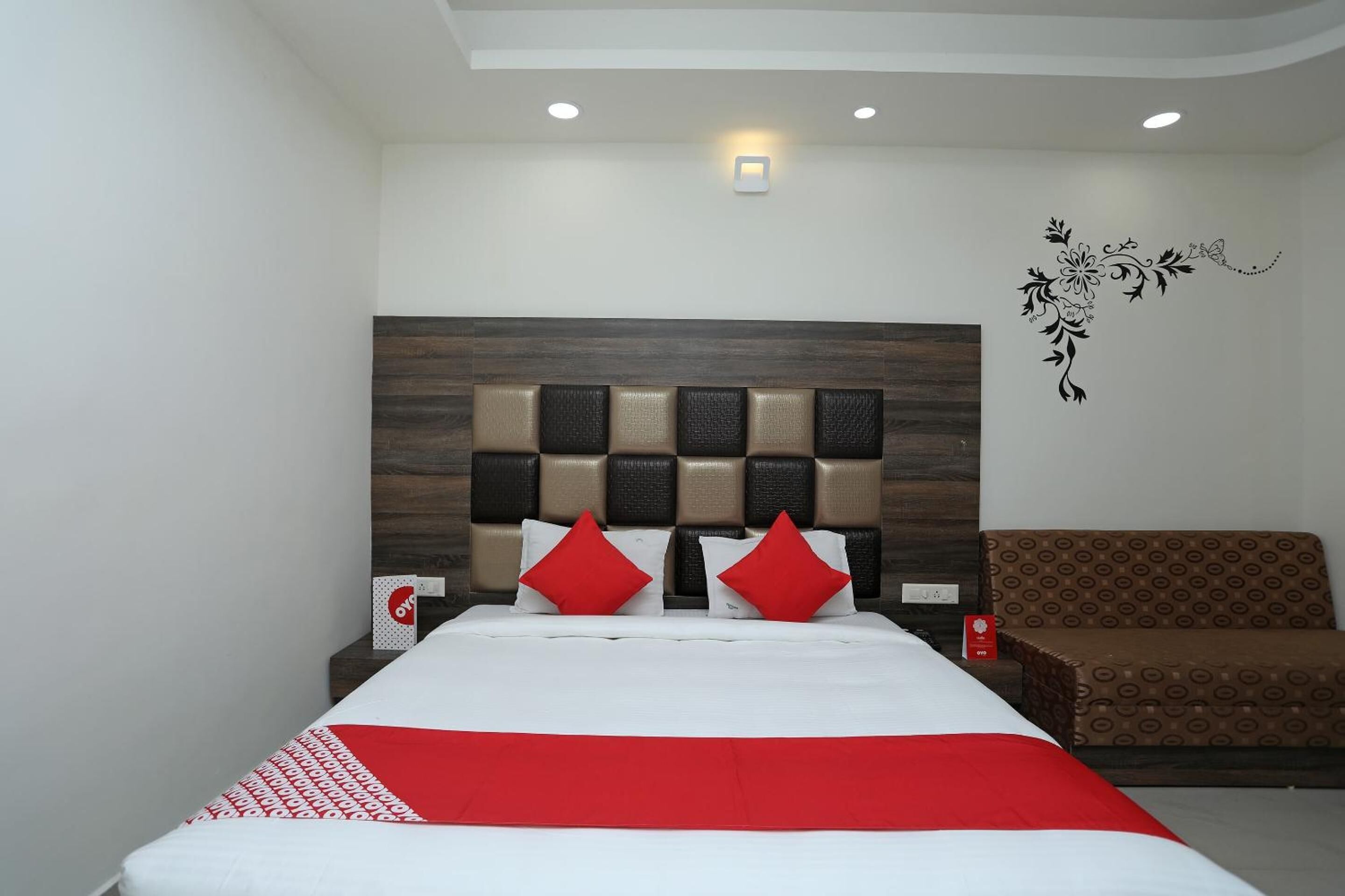 A hotel room with a bed, a nightstand, and a sofa.