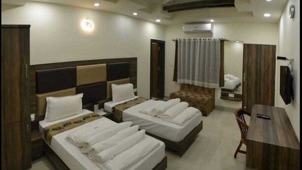 Habitación de hotel con dos camas, un escritorio, una silla y un baño.
