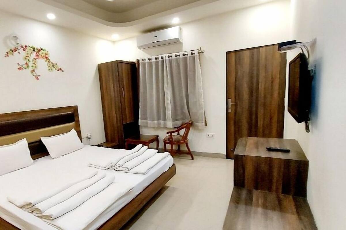 Un dormitorio con una cama, un armario de madera, un televisor y una mesita.