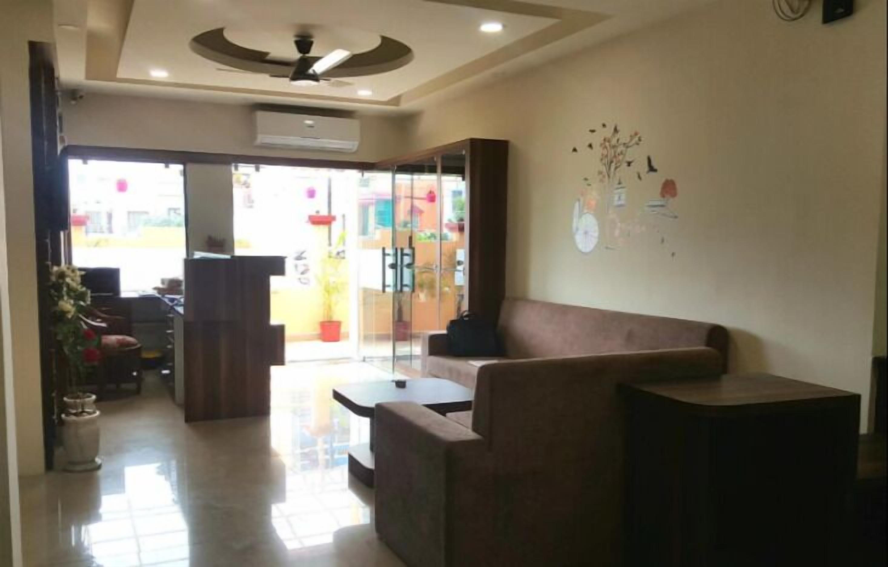 A reception area with a sofa, a coffee table, and a small table. There is a wall with a clock and decorative elements.