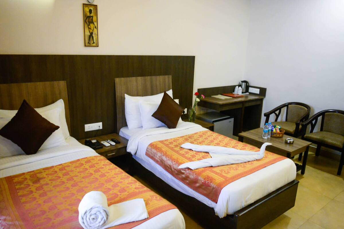 Ein Hotelzimmer mit zwei Betten, einem Schreibtisch und einem Stuhl.