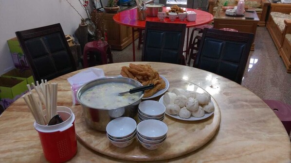 Una mesa de comedor con una olla de sopa, tazones y platos de comida.