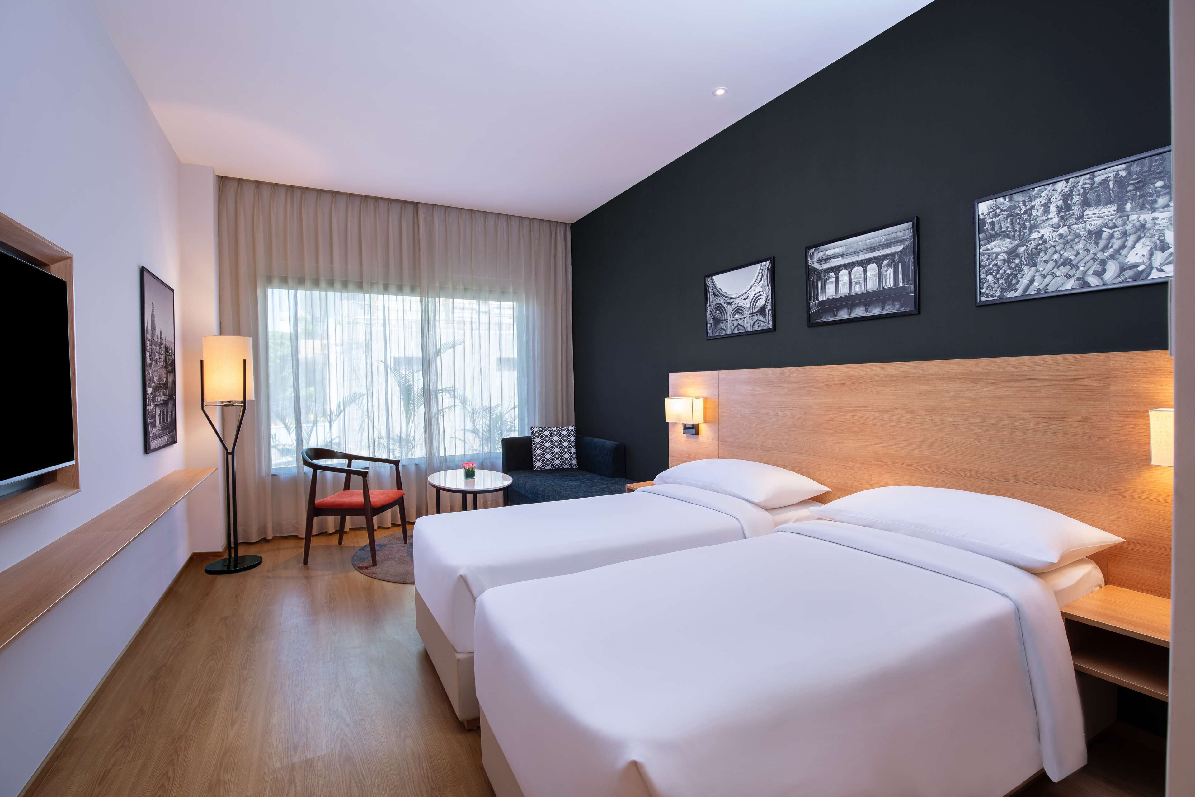 Habitació d'hotel amb dos llits, una televisió, una taula i una cadira.