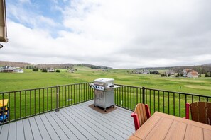 A deck with a grill, chairs, and a view of a golf course. - Luxury Dog Friendly Lodge w/ Vaulted Ceilings (Swanton)