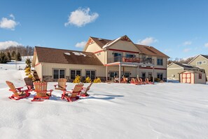 A large two-story building with a covered patio area and multiple windows. - Luxury Dog Friendly Lodge w/ Vaulted Ceilings (Swanton)
