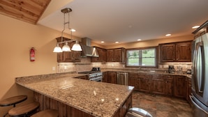 A kitchen with granite countertops, wooden cabinets, stainless steel appliances, and a window providing natural light.