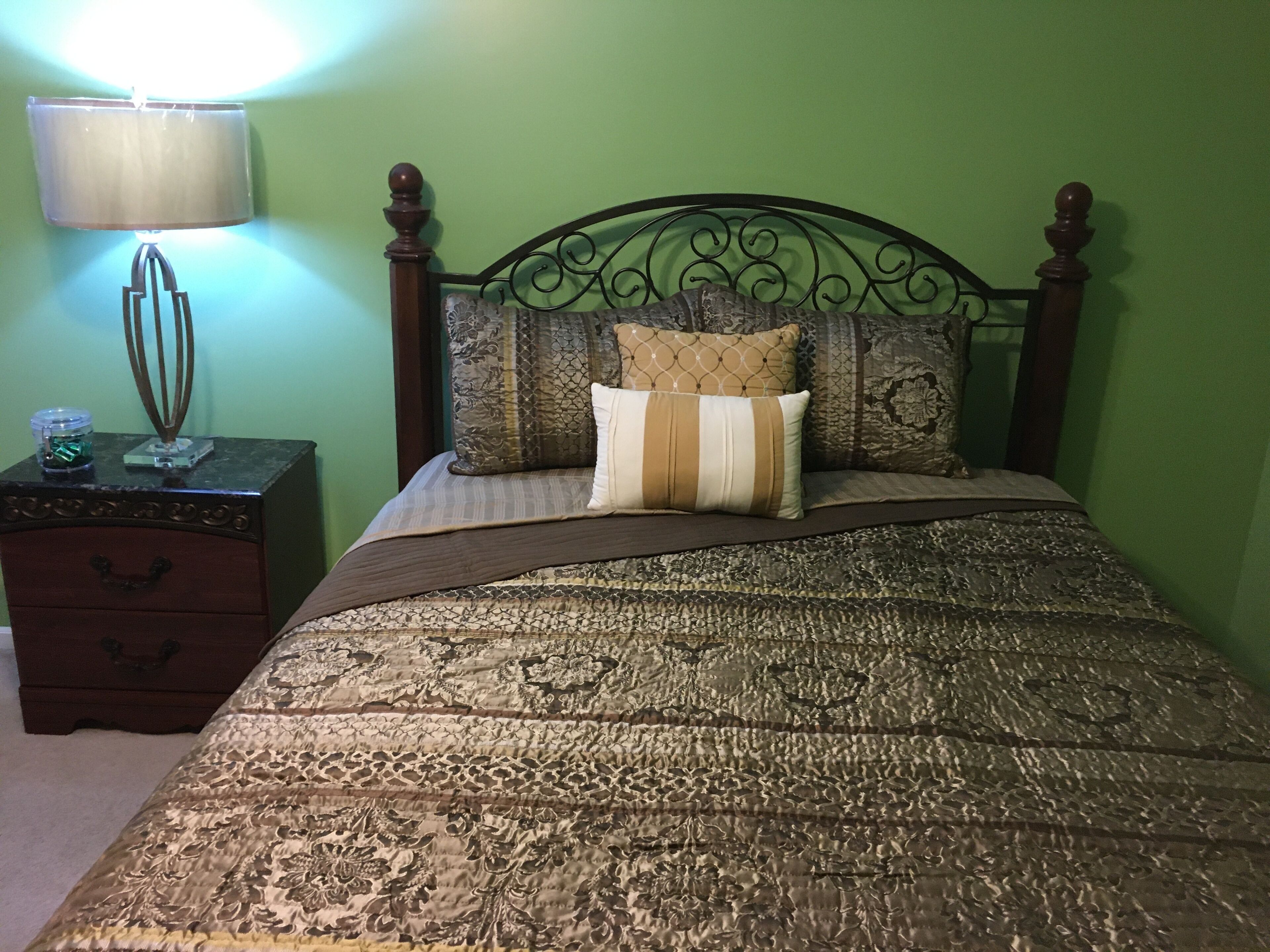 Un lit bien fait, avec une couvre-lit à motifs, un coussin décoratif et une tête de lit en bois.