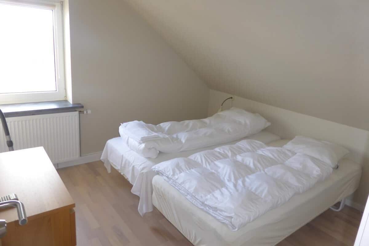 Ein kleines, sauberes Zimmer mit einem Bett, einem Schreibtisch und einem Fenster.