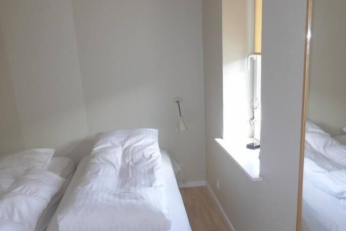 Ein Zimmer mit zwei Betten, einem Fenster und einem Spiegel.