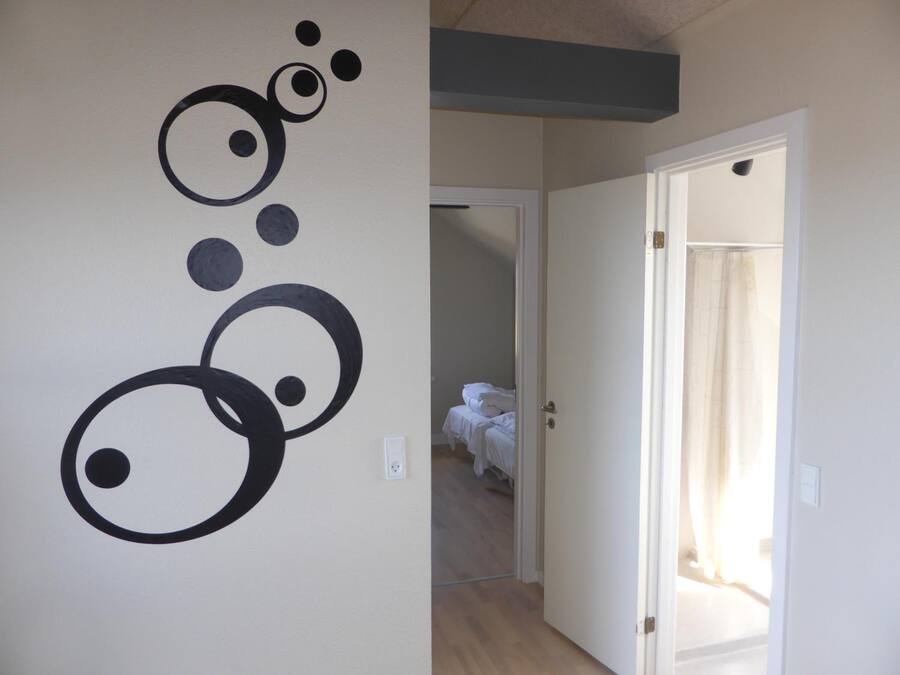 Una habitación con una cama, una puerta que da a otra estancia, y una pared decorada con una obra de arte abstracta en blanco y negro.