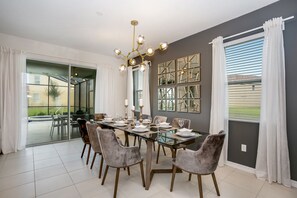 Enjoy meals in a stylish dining area with a glass-top table and plush chairs, surrounded by geometric mirror designs and large windows with views of the landscape.